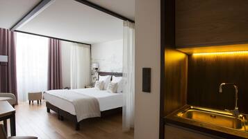 Une chambre d’hôtel comprenant un lit, un bureau, une chaise, une salle de bain avec un lavabo et un luminaire fixé au mur.