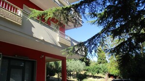 A building with a red and white facade, a balcony with a white railing, and a view of trees and a clear sky. - B&B Villa Francesca (Spoltore)