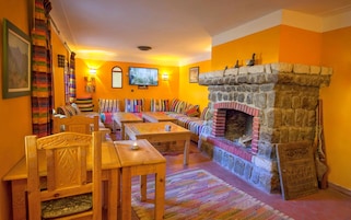 A cozy living room with a stone fireplace, colorful striped cushions, and a television mounted on the wall.