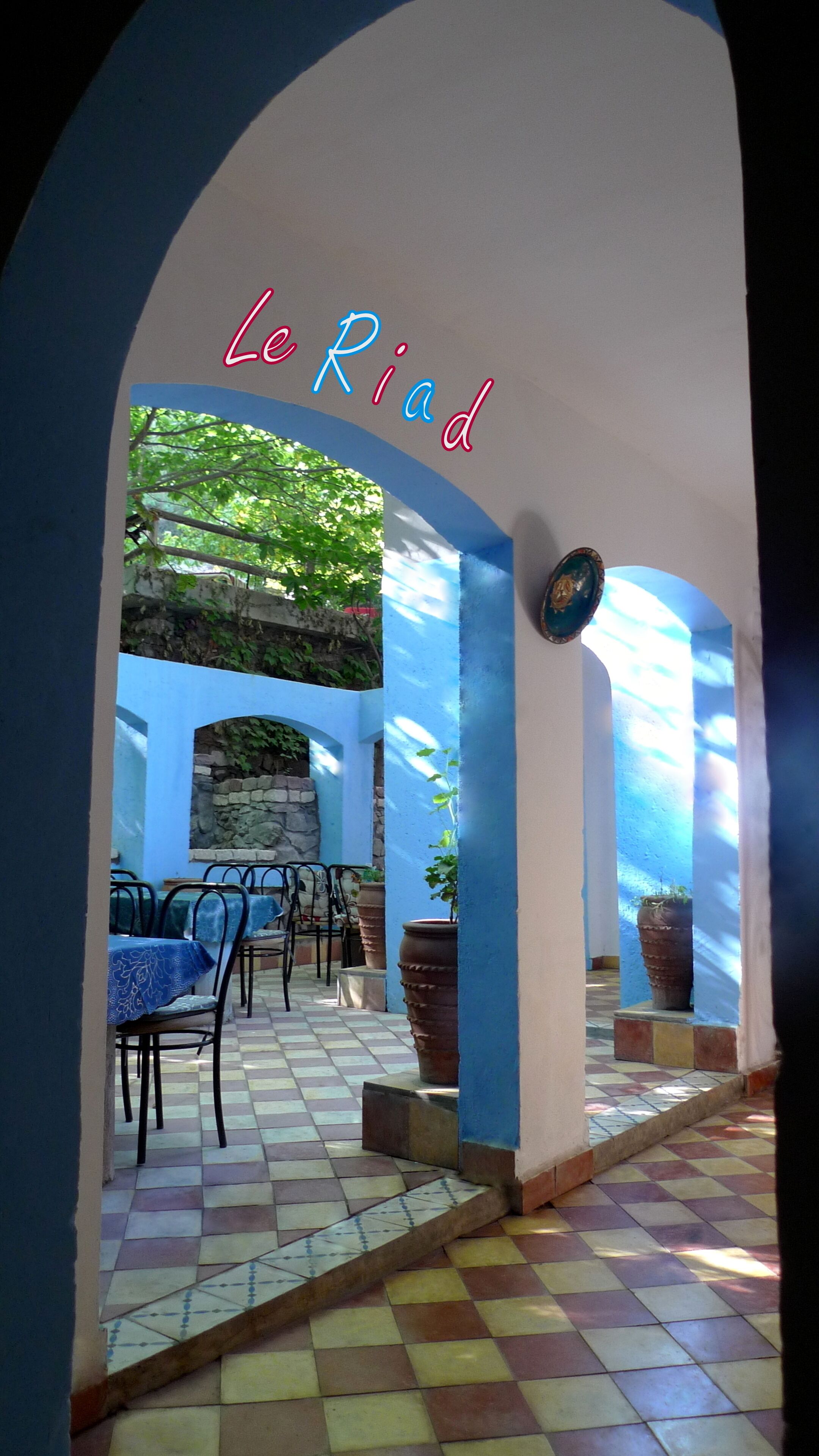 Un espace de restauration intérieur avec des murs bleus, un sol carrelé et une vue sur la verdure à l’extérieur.