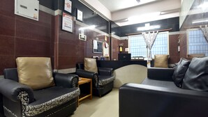 Un hall con sofás de cuero, una mesa de centro de madera y un ventilador de techo.