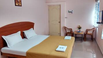 Une chambre d’hôtel avec un lit, une petite table et des chaises, une porte et un téléviseur fixé au mur.