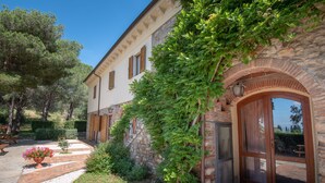 A stone building with a garden pathway, a wooden door, and a window. - Casa Vacanze Dolce Vita (Campiglia Marittima)