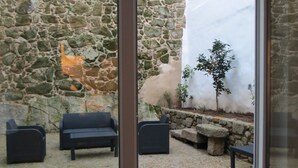 A stone courtyard with a stone wall, a small tree, and outdoor seating. - Citybreak Apartments Bolhão (Porto)