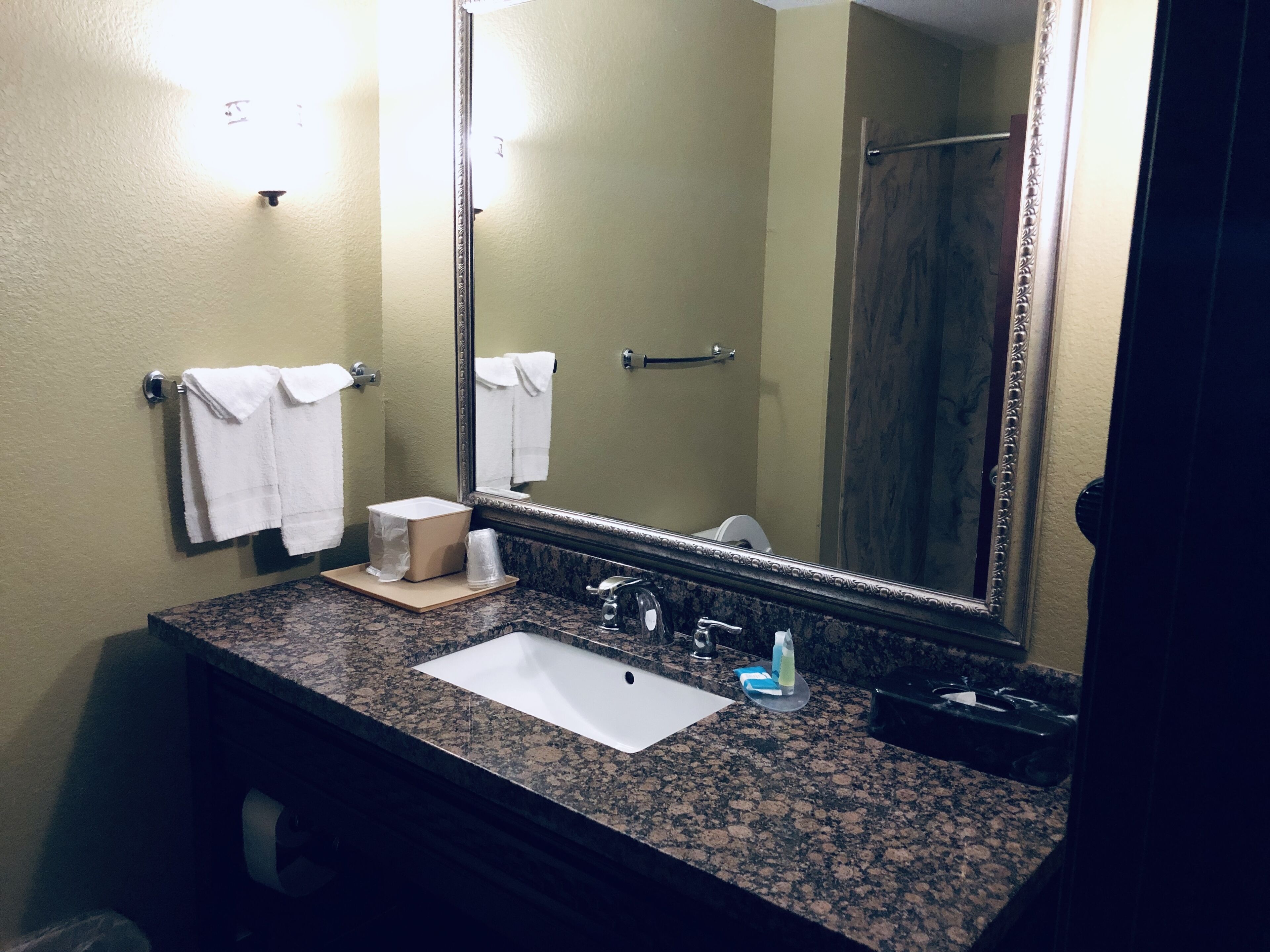 A bathroom with a sink, mirror, towel rack, and toiletries.
