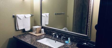 A bathroom with a sink, mirror, towel rack, and toiletries.