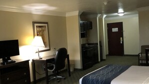 A hotel room with two beds, a desk with a lamp, a TV, and a door. - Scottish Inns (Cresson)