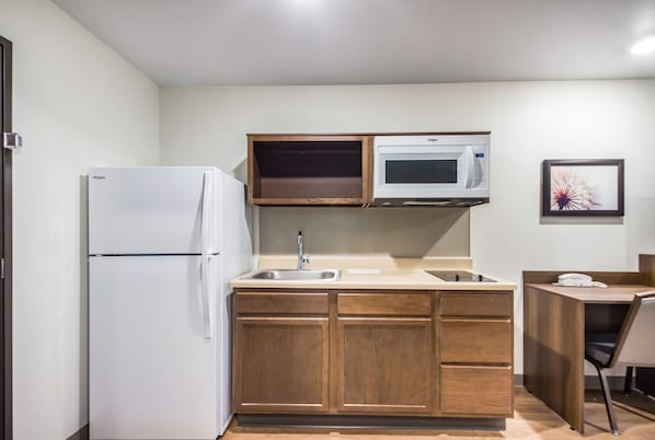 Una cocina compacta equipada con refrigerador, microondas, pileta y armarios de madera.