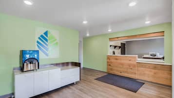 A reception area with a modern design, featuring a reception desk, a coffee machine, and a wall-mounted artwork.