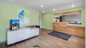 A reception area with a water dispenser, a wooden counter, and a reception desk. - WoodSpring Suites Chicago Addison (Addison)