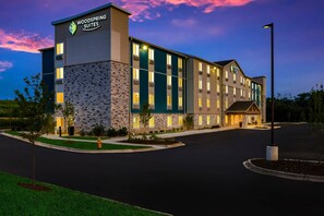 A multi-story hotel with a stone facade and a sign reading 'Woodspring Suites.'