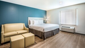 A bedroom with a bed, a sofa, and a heater. - WoodSpring Suites Chicago Addison (Addison)