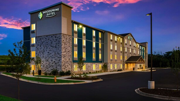 A multi-story hotel with a stone facade and a sign reading "Woodspring Suites." - WoodSpring Suites Chicago Addison (Addison)
