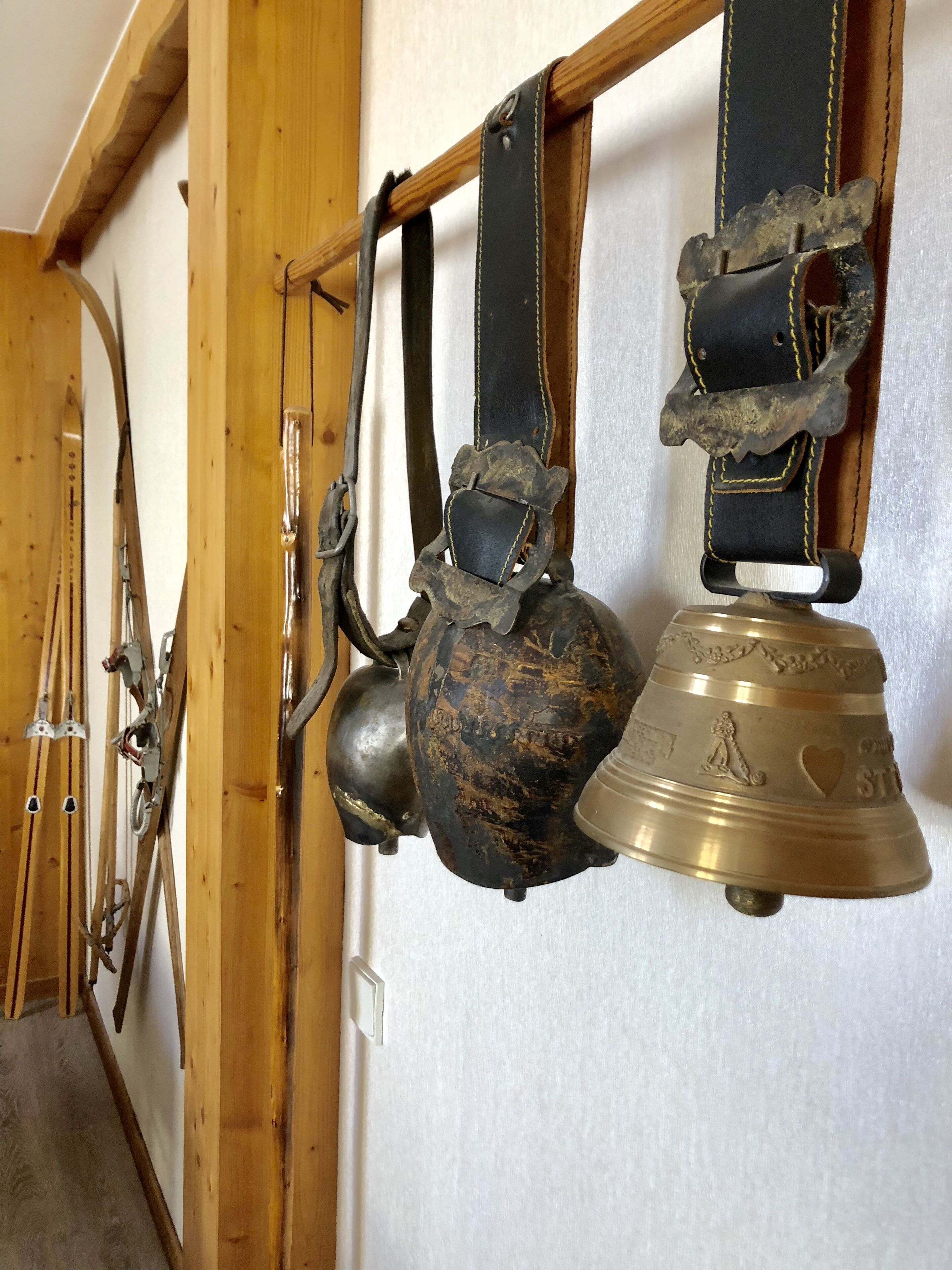 A room with wooden beams and a wall-mounted rack holding various items including a bell and a helmet.