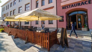 Uma área de estar ao ar livre com mesas e cadeiras de madeira, uma cerca de madeira e uma placa indicando um restaurante.