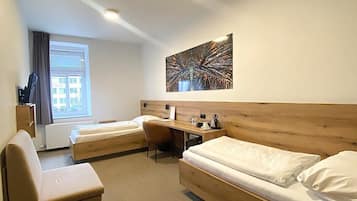 Una habitación de hotel moderna con cabecera de madera, dos camas individuales, un escritorio y una silla.