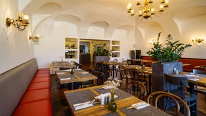 Restaurante com tetos altos em arco, mesas de madeira e assentos acolchoados.