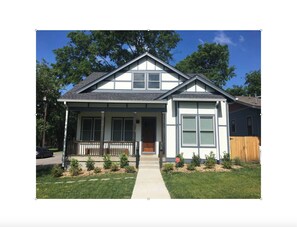 A two-story house with a front porch, a garage, and a fenced backyard.