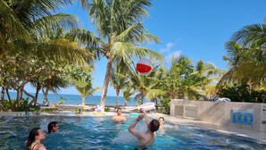 Une piscine avec une eau cristalline, des palmiers et une vue sur l’océan.