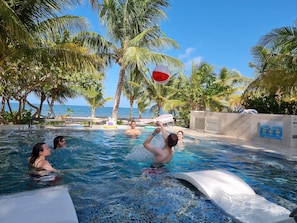 Zwembad met helder water, palmbomen en uitzicht op de oceaan.