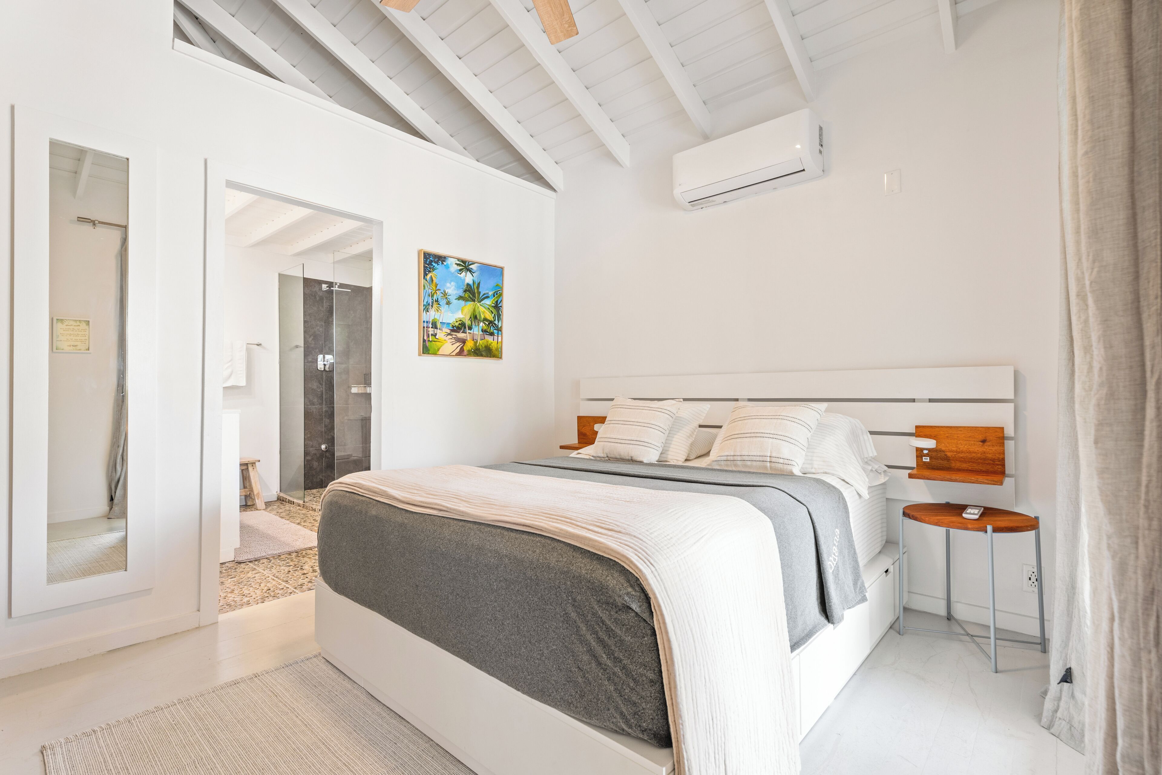 A modern bedroom with a large bed, a bedside table, and a painting on the wall.