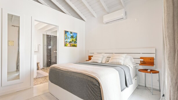 Une chambre à coucher moderne avec un grand lit, une table de chevet et un tableau au mur.