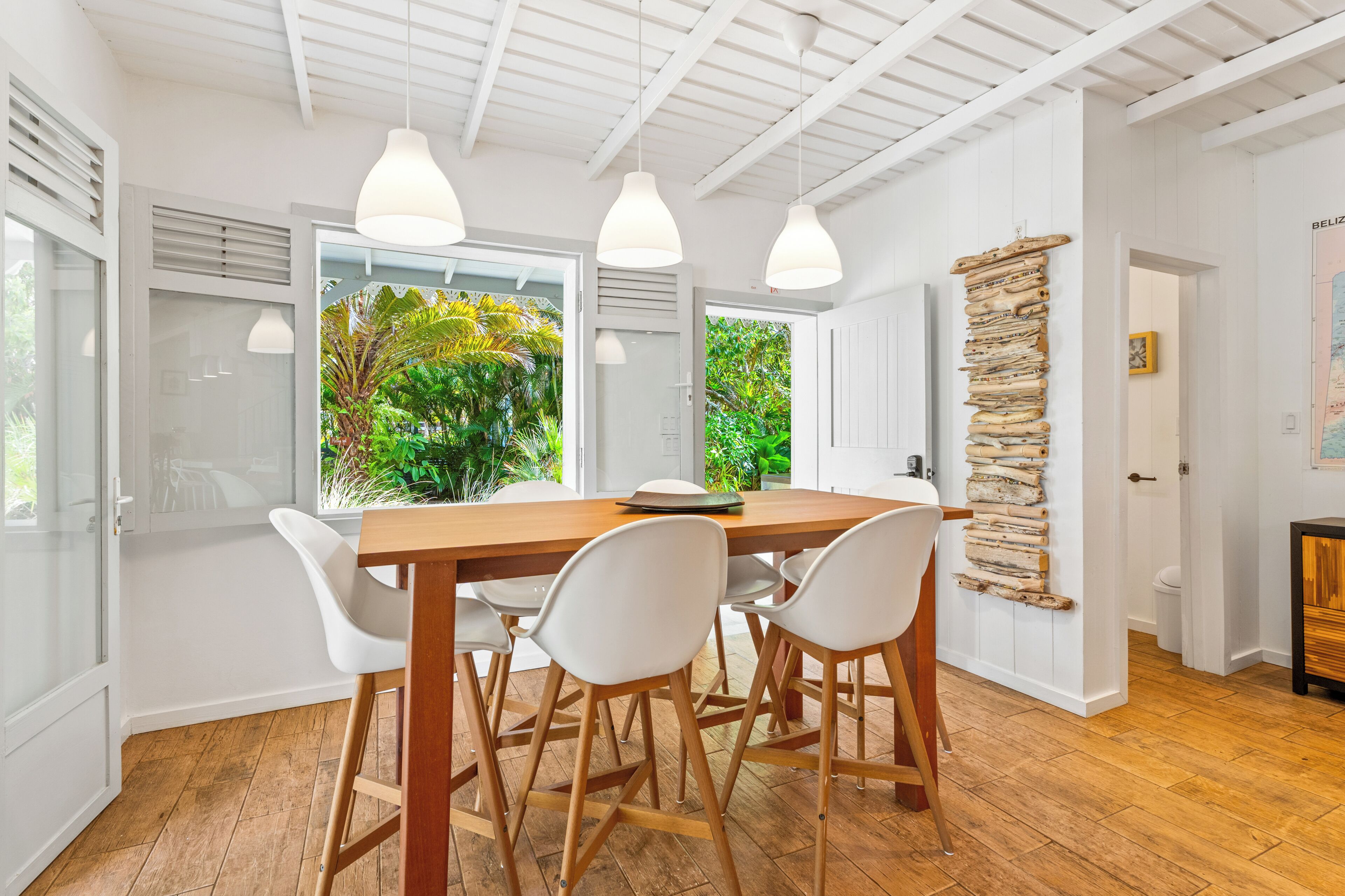A dining area with a wooden table, white chairs, and pendant lights.