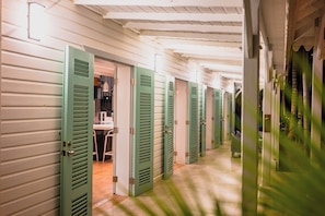 A corridor with doors leading to individual rooms, a tiled floor, and a ceiling with exposed beams. - Beachfront Family vacation Home with private chef and housekeeping - privacy ! (Placencia village)
