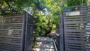 A pathway leading through a lush garden with wooden gates labeled "OHANA".