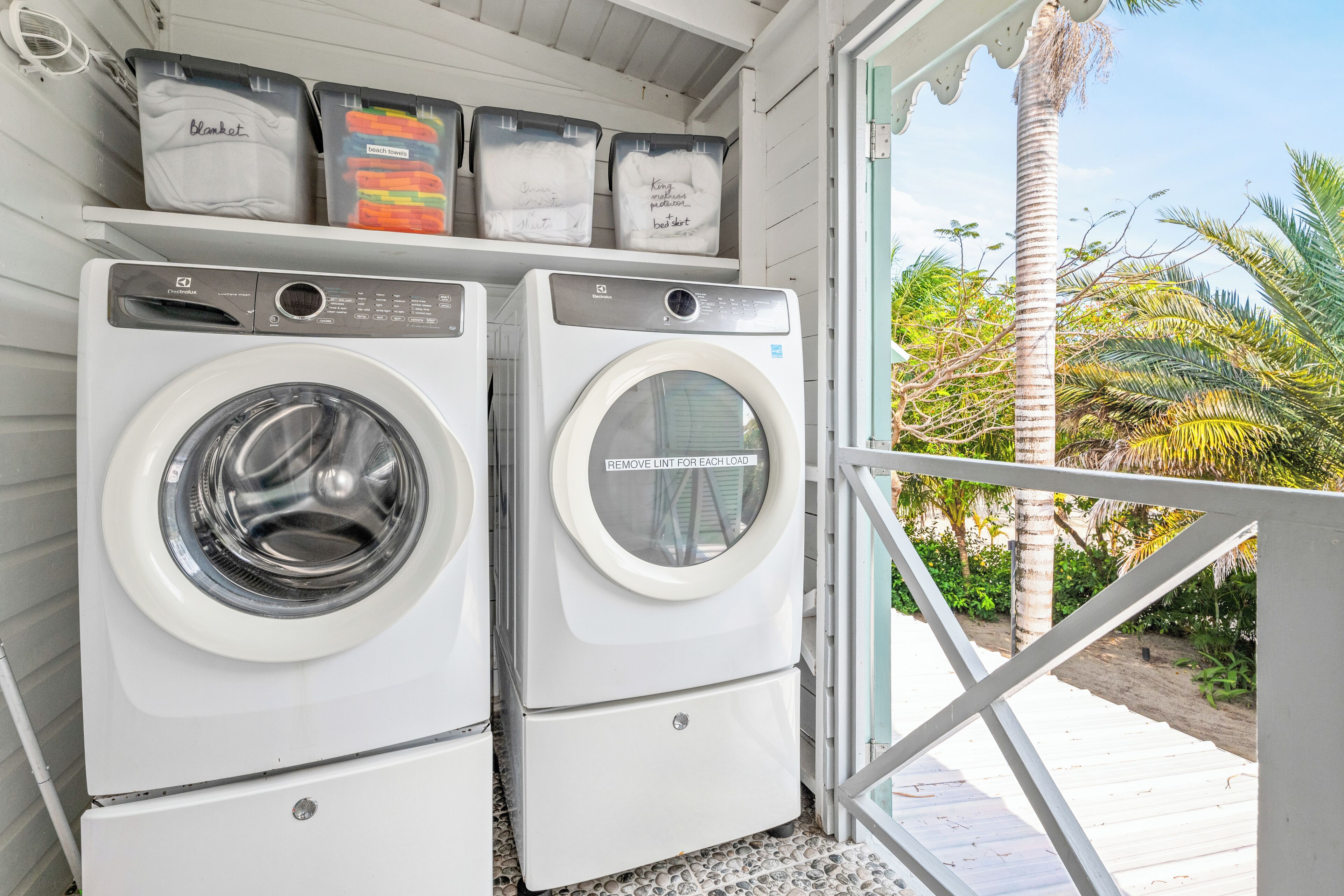 Two front-loading washing machines with a shelf above them containing folded towels.
