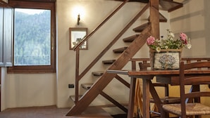 A wooden staircase with a rustic design, a dining table with chairs, and a vase of flowers. - Agriturismo Il Casalino (Spoleto)