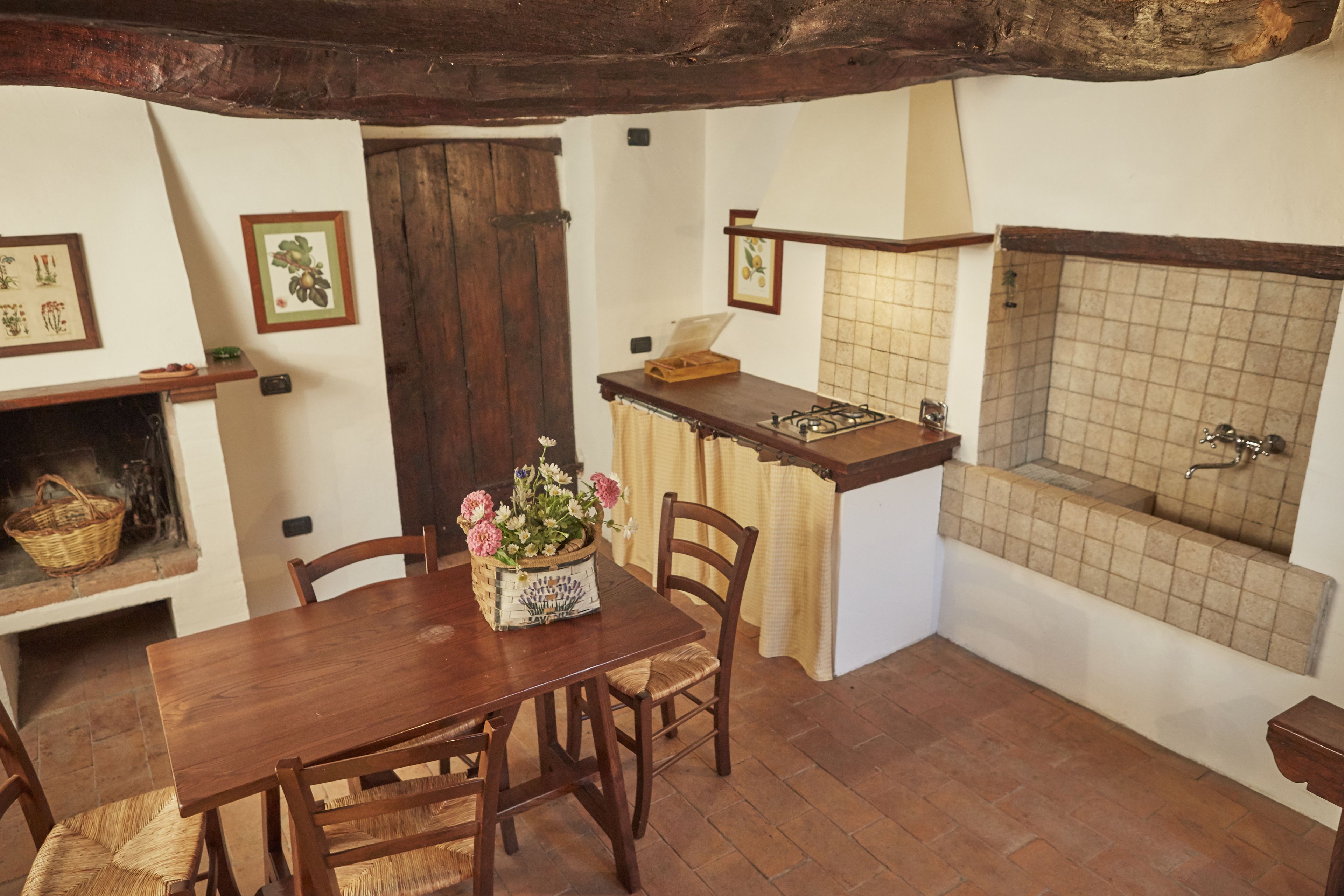Una cucina rustica con un tavolo di legno, sedie, un fornello a gas e uno schienale piastrellato.