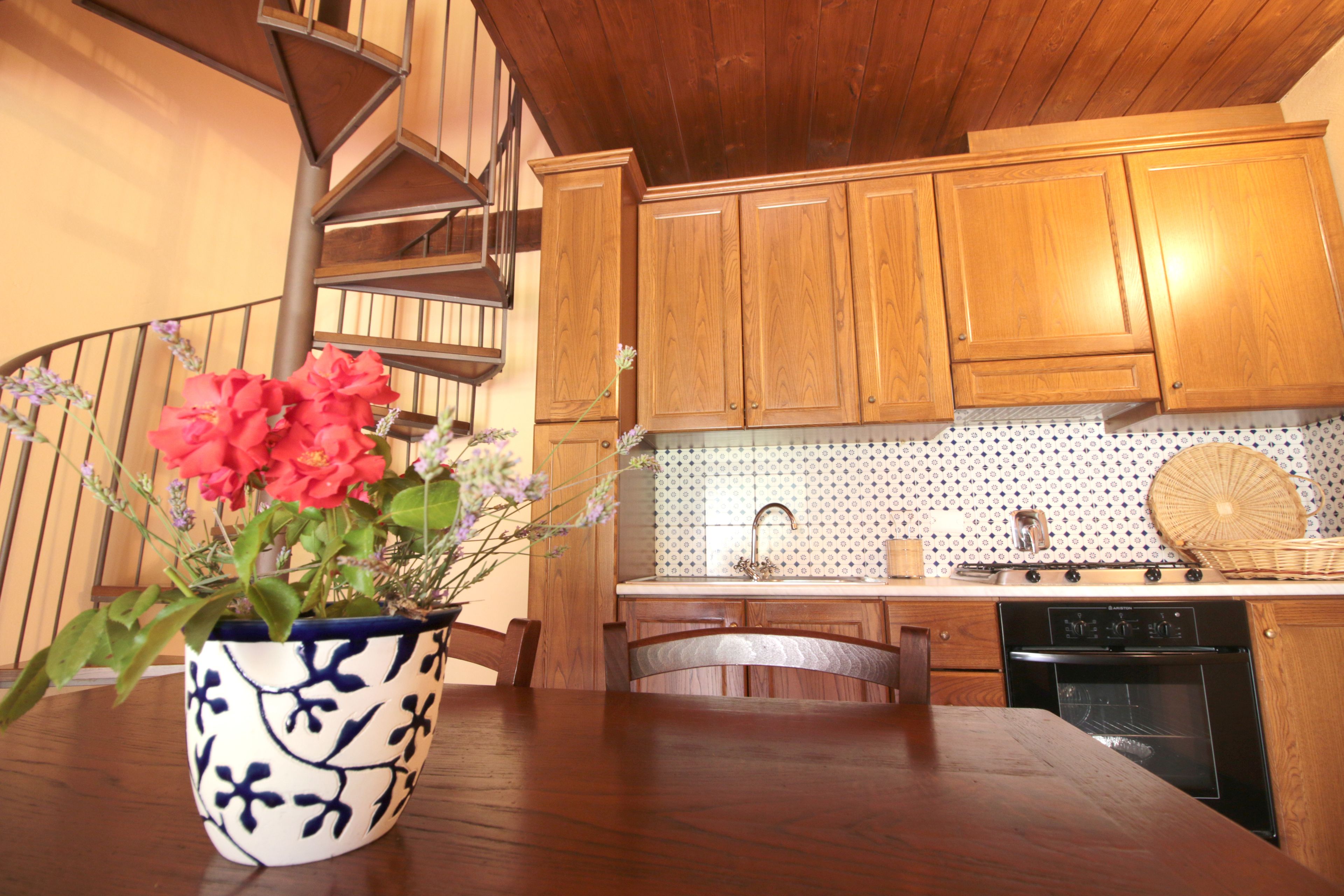 A kitchen with wooden cabinets, a built-in oven, and a potted plant on the counter.