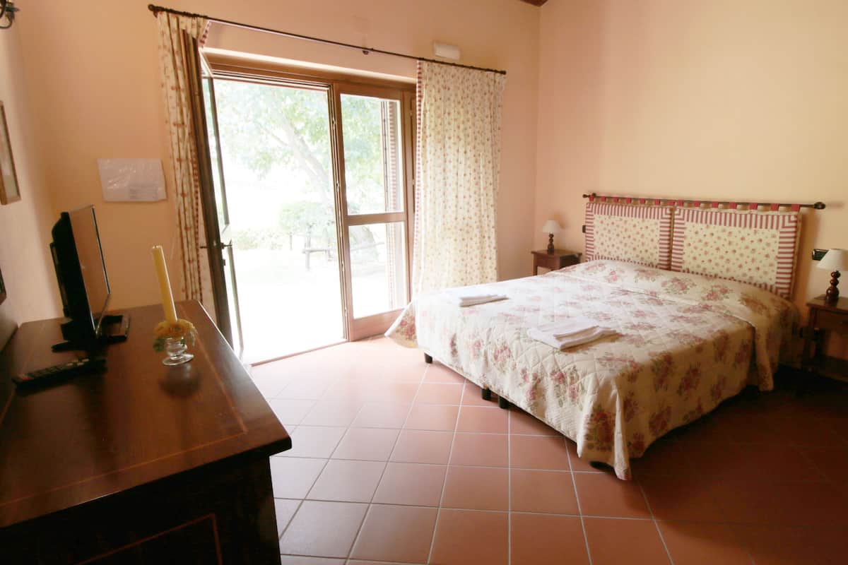 Ein Schlafzimmer mit Bett, Schreibtisch, Lampe und einem Fenster mit Vorhängen.