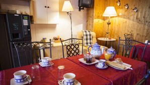 A dining area with a red tablecloth, tea set, and a coffee machine. - Hostal Chinchon (Chinchon)