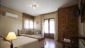 A hotel room with a bed, a chair, a desk, an air conditioner, a television, and a wardrobe. - Hostal Chinchon (Chinchon)