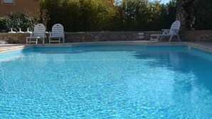 Una piscina cristalina con sillones de descanso blancos alrededor.