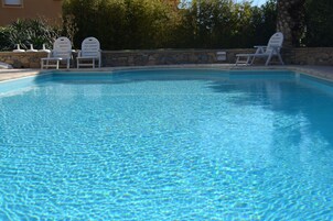 Una piscina al aire libre, sillones reclinables de piscina