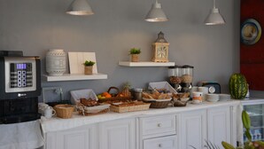 Una cocina con armarios blancos, una cafetera, lámparas colgantes y diversos alimentos sobre la encimera.