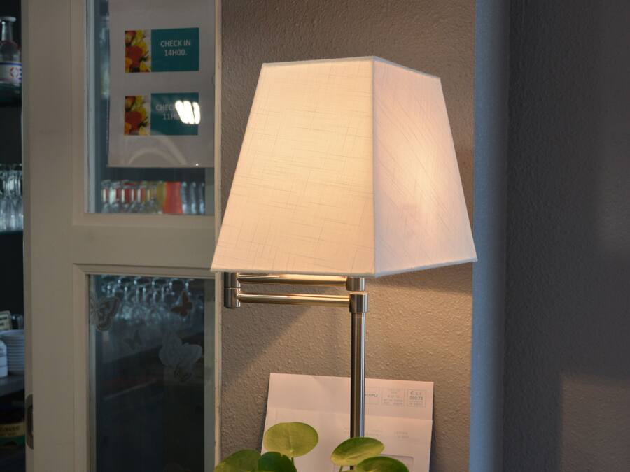 A reception desk with a lamp, a potted plant, and a sign that reads "Aimer la vie ET Vivre pour aimer!"
