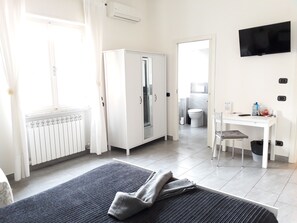 Ein Hotelzimmer mit einem Bett, einem Schreibtisch, einem Kleiderschrank und einem Badezimmer im Hintergrund.