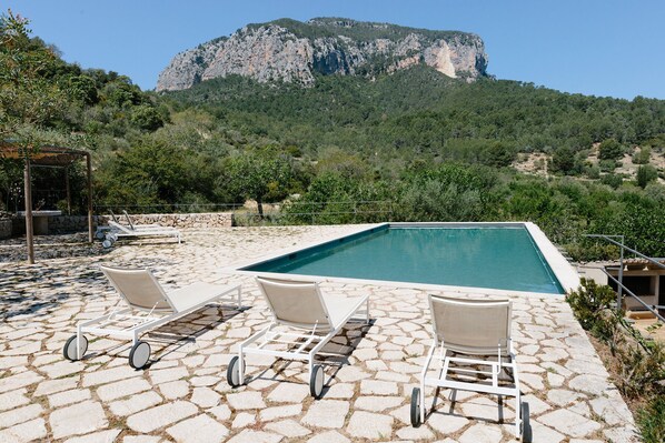 A pool area with lounge chairs and a view of a mountain. - Agroturismo Filicumis (Lloseta)