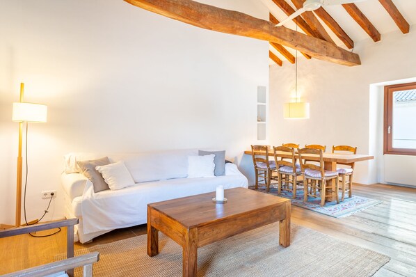A cozy living room with a wooden coffee table, a sofa, and a dining table with chairs. - Agroturismo Filicumis (Lloseta)