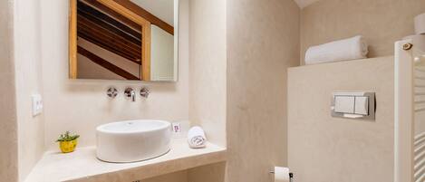 A modern bathroom with a large sink, mirror, and towel rack.