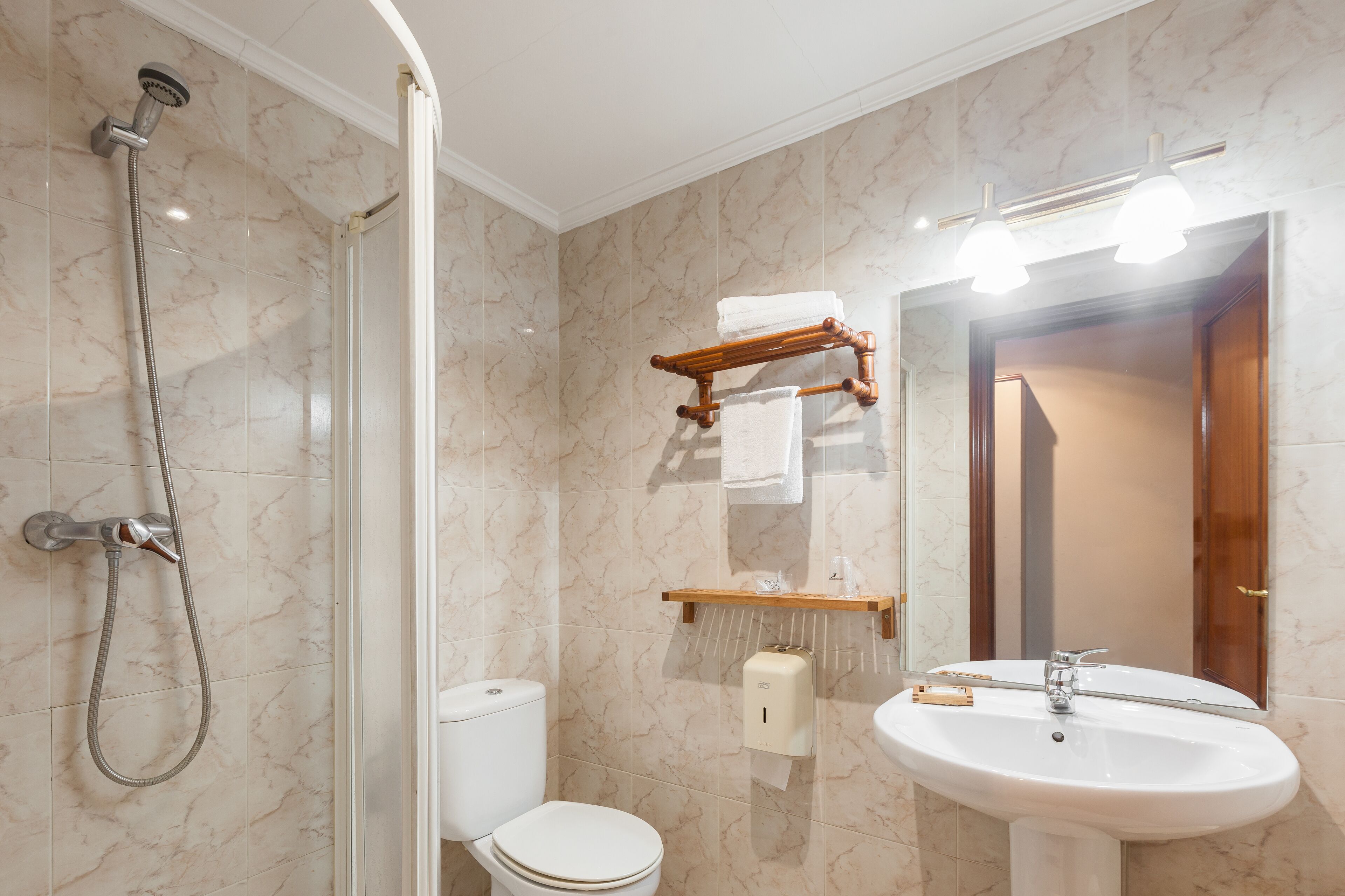 Baño con ducha, inodoro, lavabo y espejo.