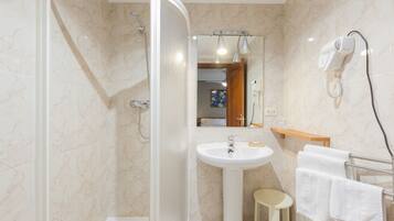 A modern bathroom with a shower, sink, and towel rack.