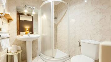 Un baño moderno con ducha de vidrio, lavamanos e inodoro.