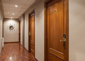 Un pasillo con puertas de madera, un reloj en la pared y un radiador.