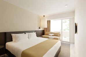 Habitación de hotel con una cama grande, un sofá, una mesita y vistas al exterior.