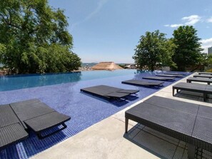 Una piscina con sillones de descanso y vistas del paisaje.